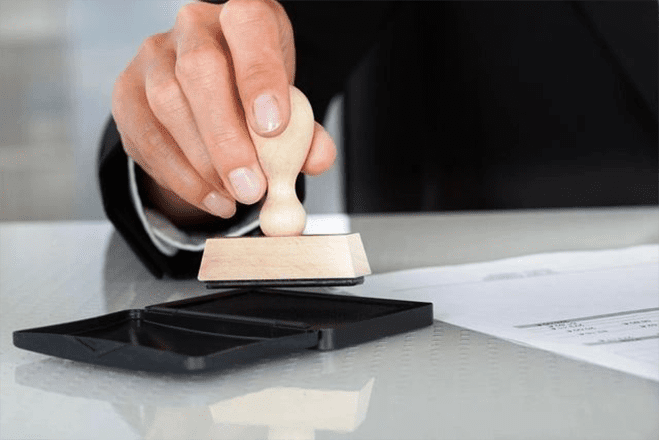 A person is stamping a document with a rubber stamp.