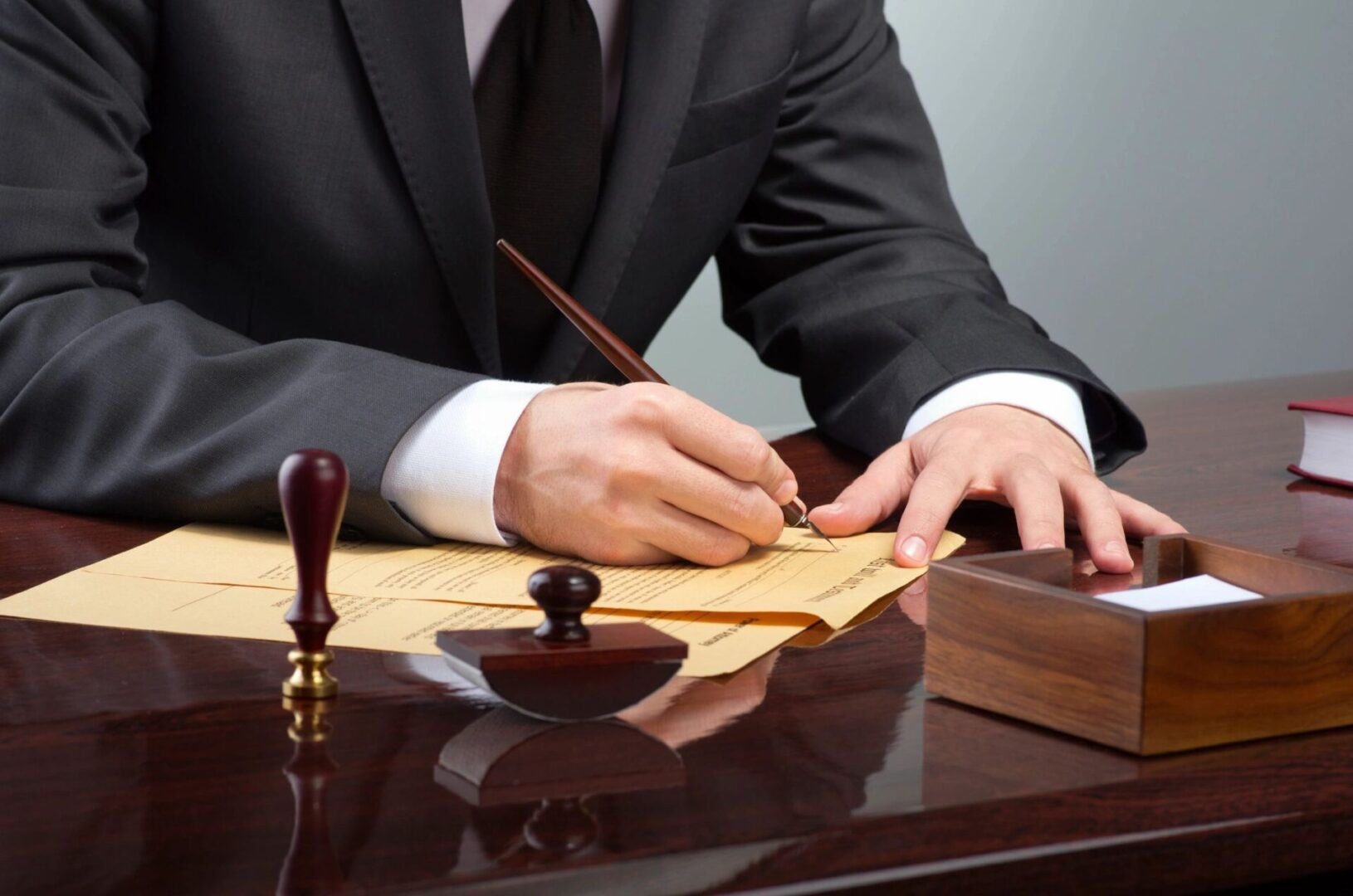 A man in a suit signing a document at a desk.