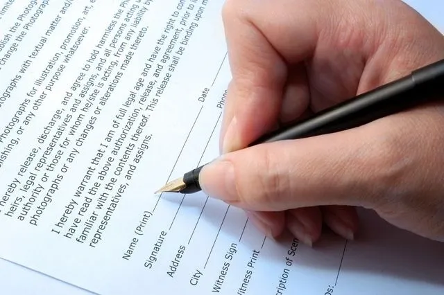 A person signing a document with a pen.